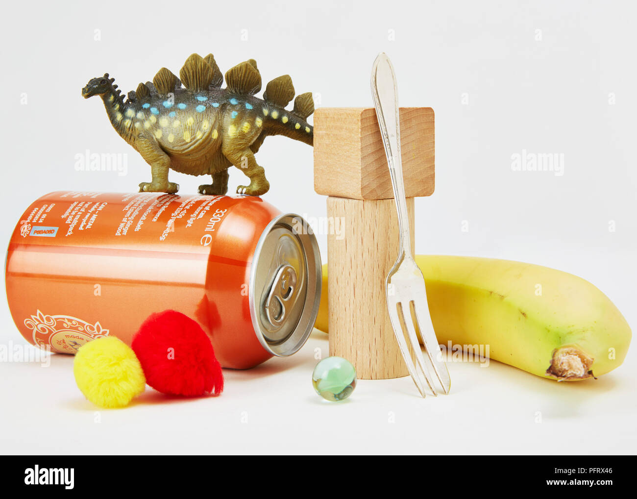 Everyday non-magnetic objects including rubber dinosaur, aluminium can, woolly pompoms, wood blocks, silver fork, banana and marble Stock Photo