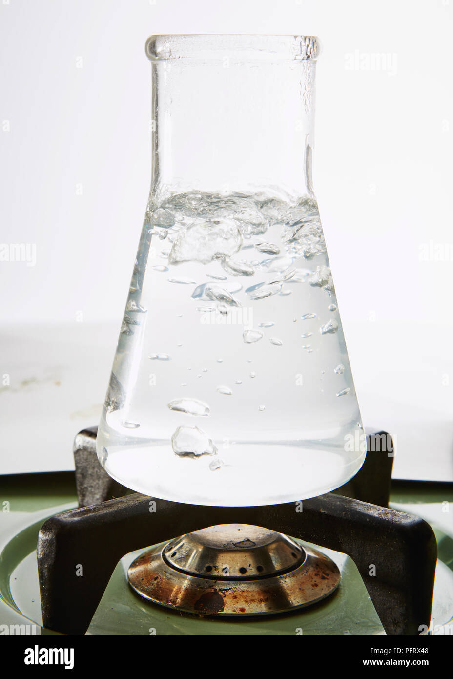 Glass conical flask containing water  being boiled Stock Photo