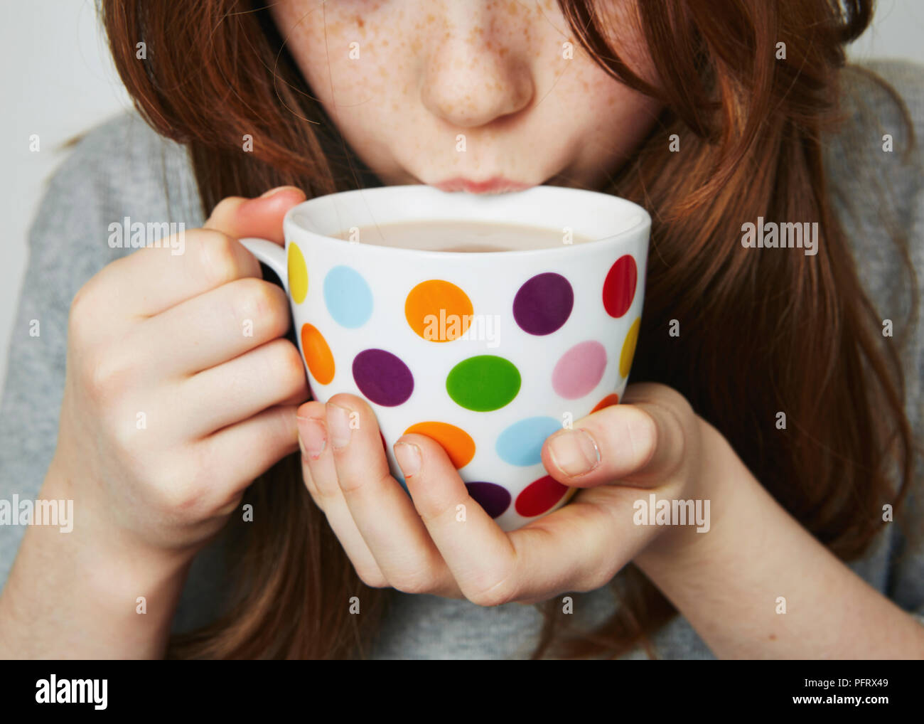 Child drinking a hot drink from a spotty mug Stock Photo