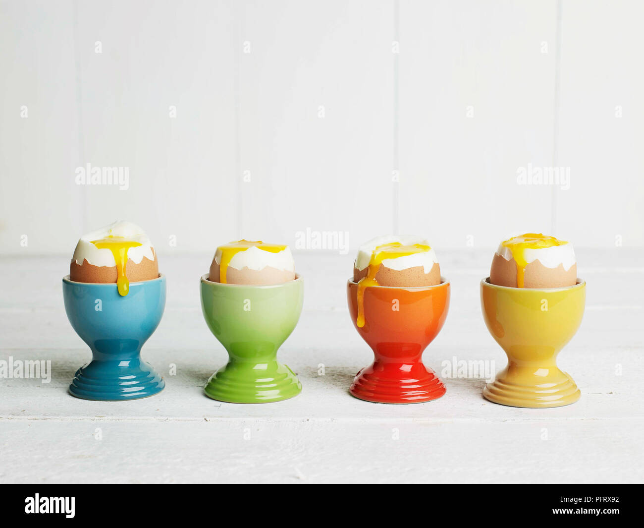 Soft-boiled eggs in coloured egg cups Stock Photo