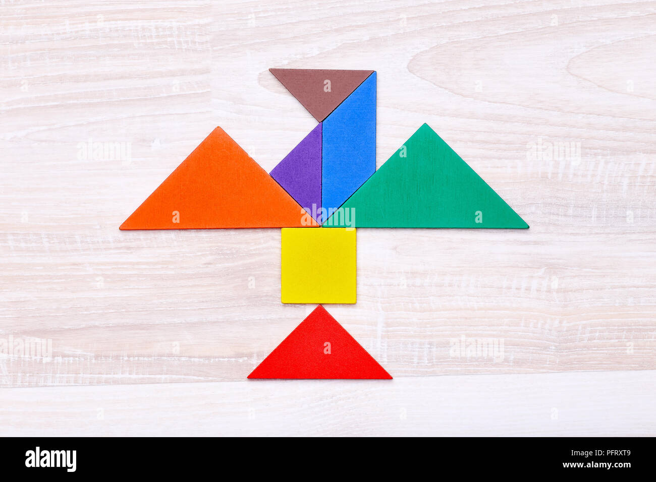 From above tangram figures into shape of eagle on wooden table in the center Stock Photo