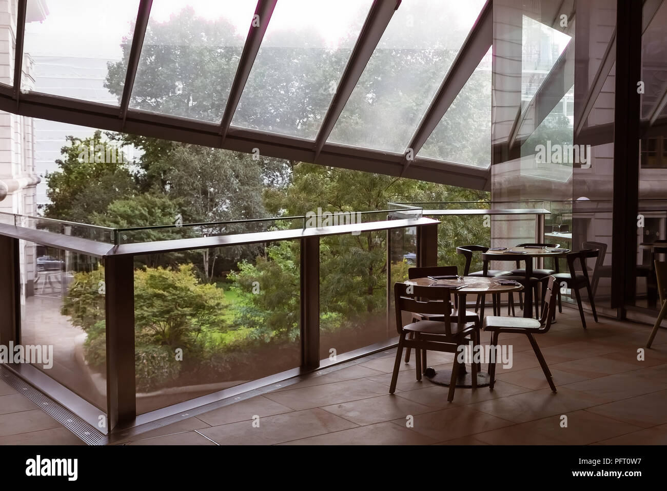 picture of cafe table and chairs standing on a balcony of a trade center under a glass roof Stock Photo