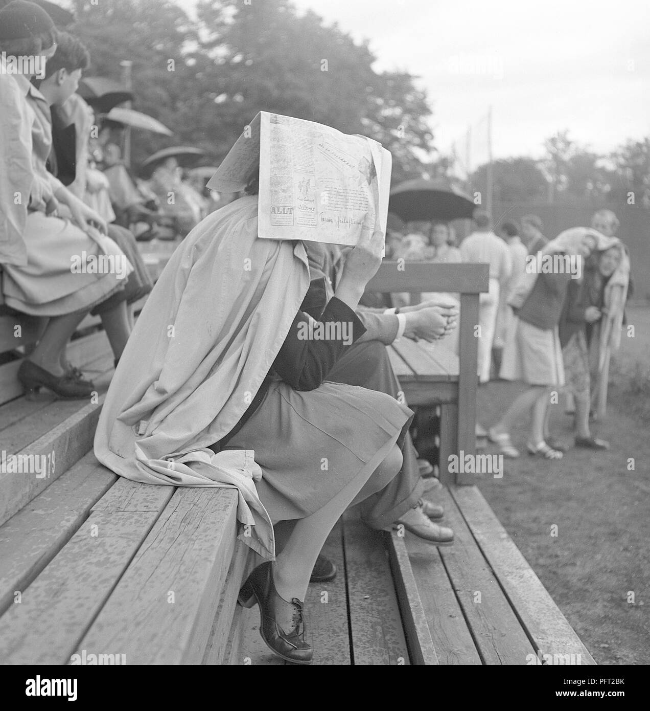 1940s woman in the rain. A  woman covers her head with a newspaper to avoid getting wet in the rainy weather. Sweden 1940s ref K48-3 Stock Photo