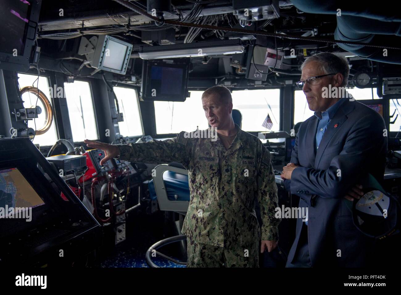 Everett, Wash. (May 31, 2018) Washington State Governor Jay Inslee tours the bridge of the Arleigh Burke-class guided-missile destroyer USS Ralph Johnson (DDG 114) with Cmdr. Jason Patterson, Ralph Johnson's commanding officer. Ralph Johnson is the sixth and most recent destroyer to be home-ported in Naval Station Everett. Stock Photo