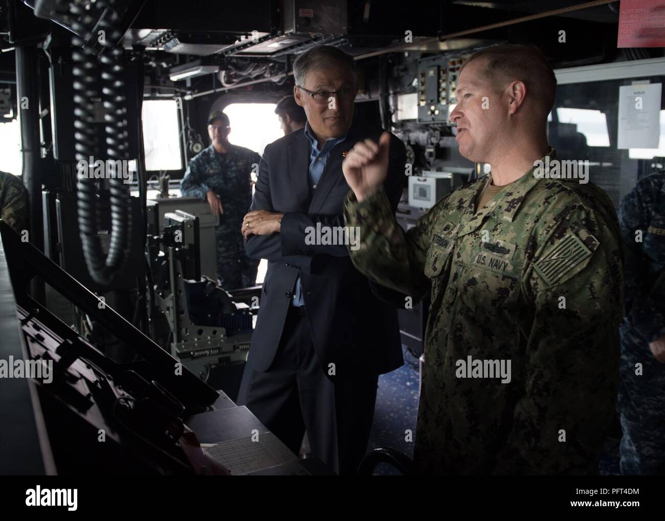 Everett, Wash. (May 31, 2018) Washington State Governor Jay Inslee tours the bridge of the Arleigh Burke-class guided-missile destroyer USS Ralph Johnson (DDG 114) with Cmdr. Jason Patterson, Ralph Johnson's commanding officer. Ralph Johnson is the sixth and most recent destroyer to be home-ported in Naval Station Everett. Stock Photo