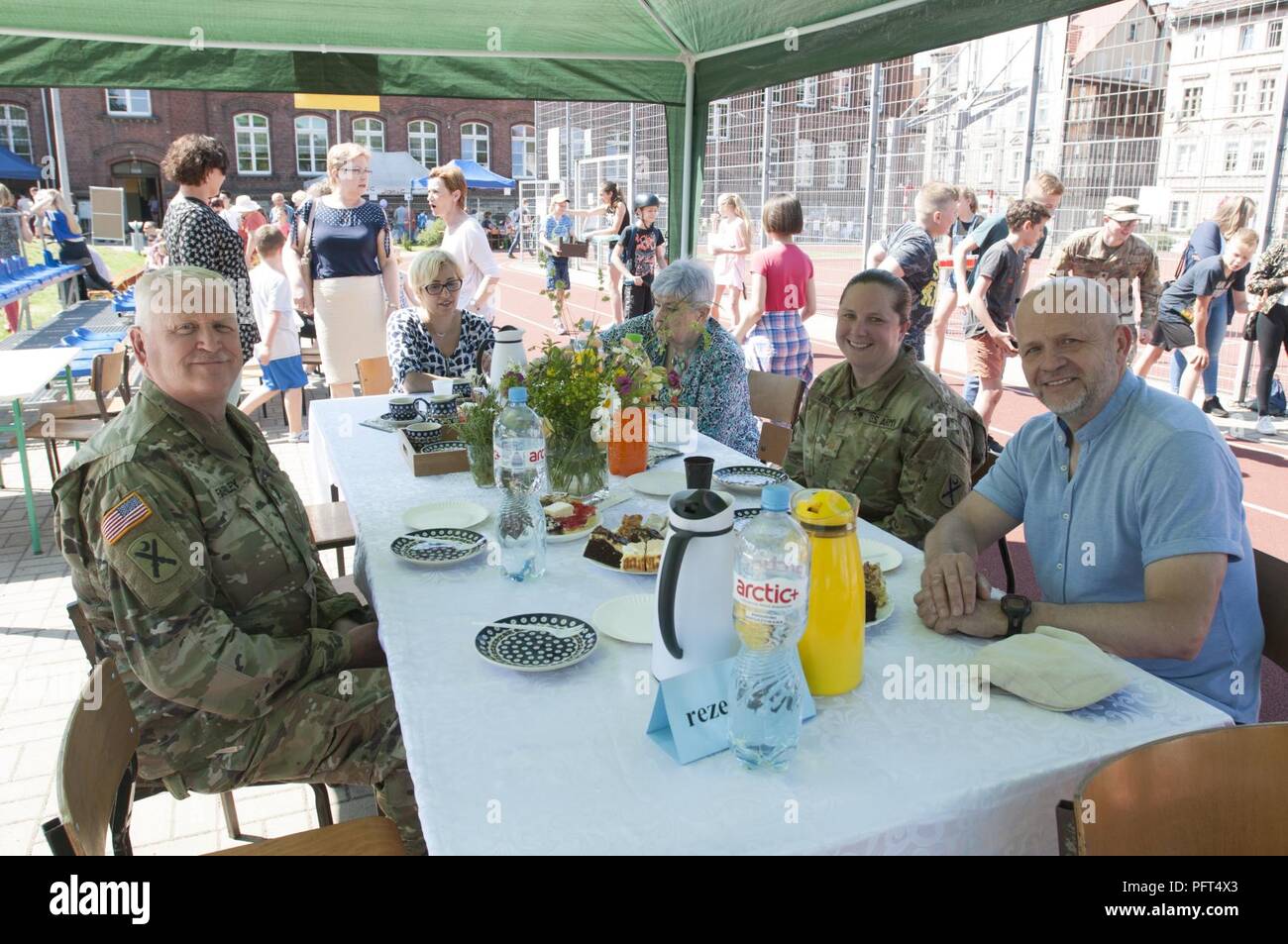 U.S. Army Sgt. Maj. Samuel Farley (right) and Maj. Emily Lynds (left), both assigned to Resolute Castle 18, 218th Maneuver Enhancement Brigade, South Carolina Army National Guard, have dessert with Kornel Filipowicz, the vice president of Boleslawiec, Poland, during the Boleslawiec Primary School Number 4 festival in Boleslawiec, Poland, May 26, 2018. Resolute Castle Soldiers were special guests of the festival and participated in sporting events and pottery painting with the primary school children. Stock Photo