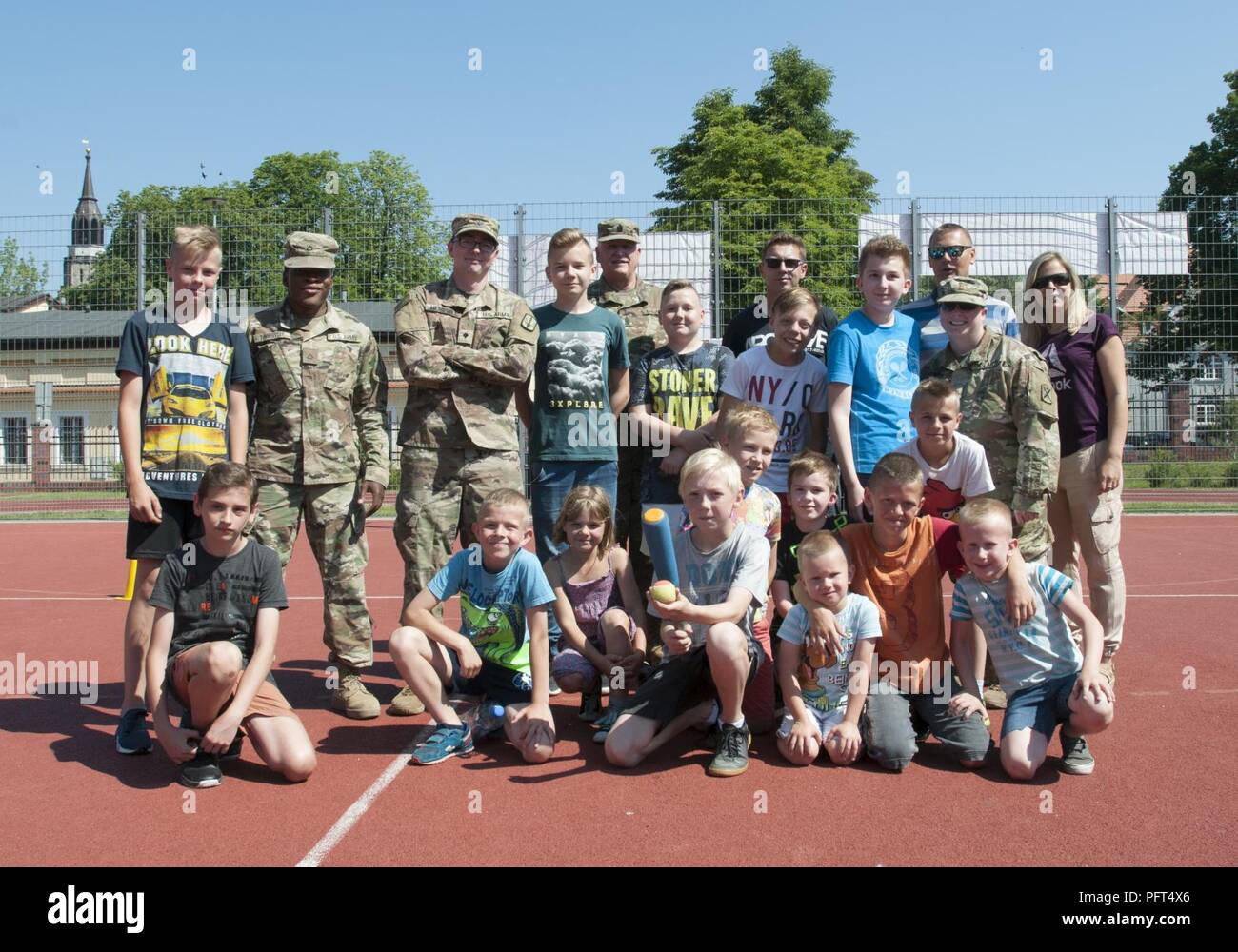 U.S. Army Soldiers assigned to Headquarters and Headquarters Company, 218th Maneuver Enhancement Brigade and Company B, 151st Expeditionary Signal Battalion, both with the South Carolina Army National Guard, pose for a group photo after playing a baseball game with Boleslawiec Primary School Number 4 students during their school festival in Boleslawiec, Poland, May 26, 2018. The Soldiers were special guests of the festival and participated in sporting events and pottery painting with the primary school children. Stock Photo