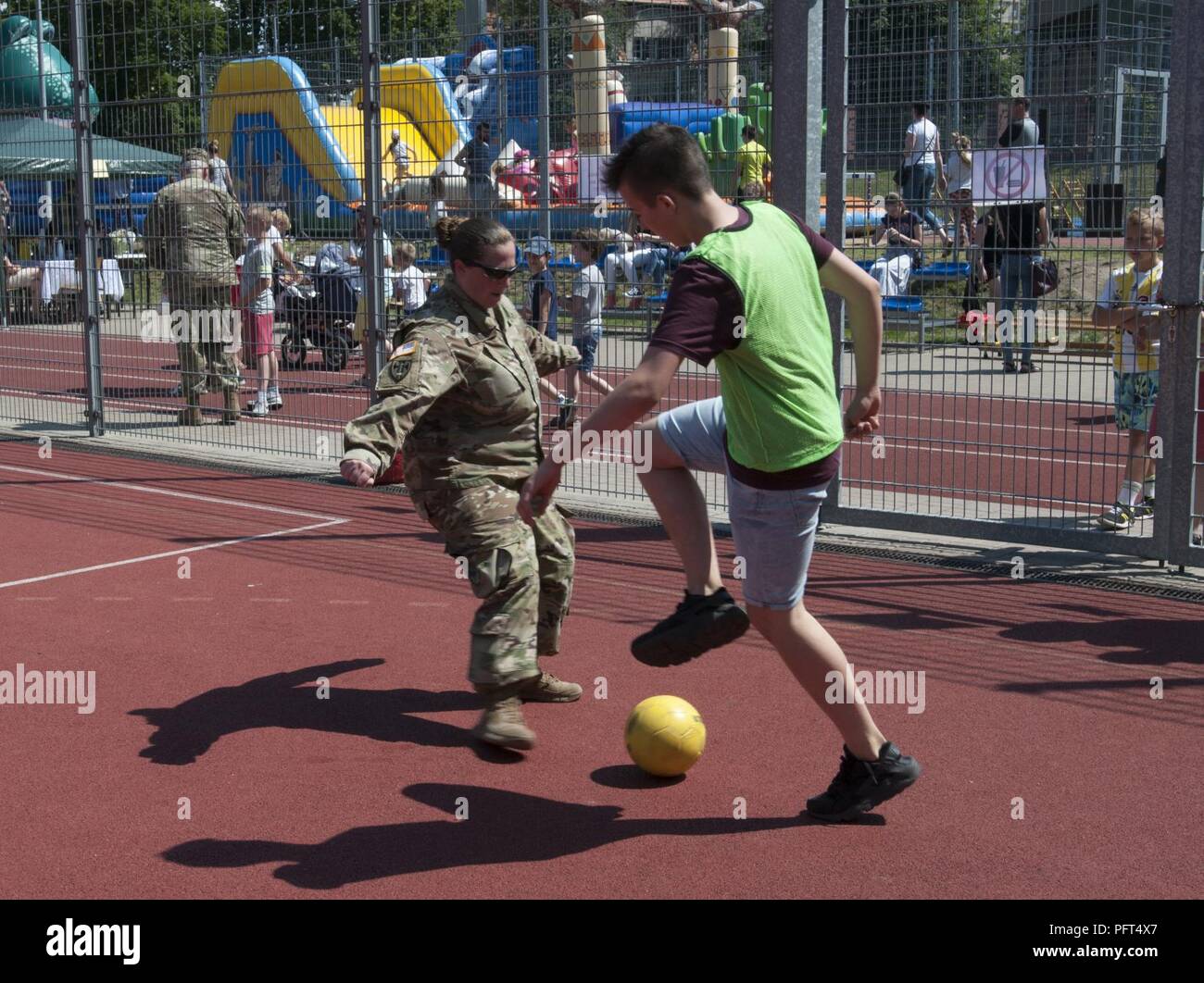 U.S. Army Maj. Emily Lynds, personnel officer assigned to Resolute Castle 18, 218th Maneuver Enhancement Brigade, South Carolina Army National Guard, plays soccer against a student from Boleslawiec Primary School Number 4 during their school festival in Boleslawiec, Poland, May 26, 2018. Resolute Castle Soldiers were special guests of the festival and participated in sporting events and pottery painting with the primary school children. Stock Photo