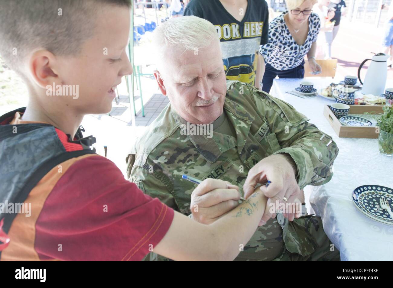 U.S. Army Sgt. Maj. Samuel Farley, logistics noncommissioned officer in charge for Resolute Castle 2018, assigned to 218th Maneuver Enhancement Brigade, South Carolina Army National Guard, autographs a student’s arm during the Boleslawiec Primary School Number 4 festival in Boleslawiec, Poland, May 26, 2018. Resolute Castle 18 Soldiers were special guests of the festival and participated in sporting events and pottery painting with the primary school children. Stock Photo