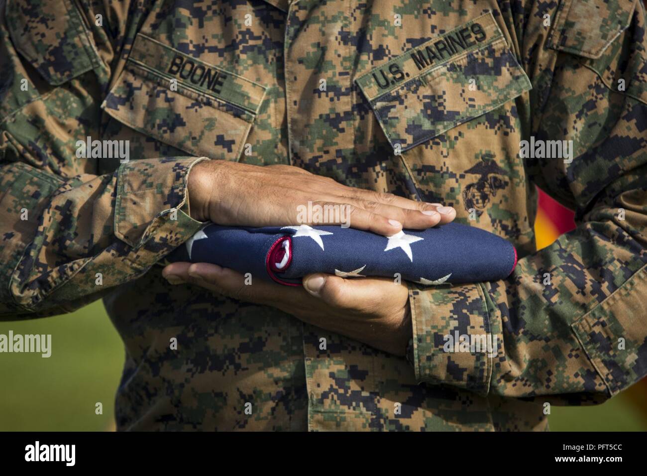 U.S. Marine Corps Sgt. Maj. Aaron Boone, a battalion sergeant major with 2nd Assault Amphibian Battalion (AABn), 2nd Marine Division, holds a tri-fold American flag for a Memorial Day ceremony during a deployment for training (DFT) exercise at Fort Stewart, Ga., May 28, 2018. Boone held the flag in front of the battalion to honor the fallen service members from the battalion as well as those throughout the Department of Defense. The DFT is to maintain proficiency in landing the surface assault element during amphibious operations to inland objectives and with conduction mechanized operations a Stock Photo