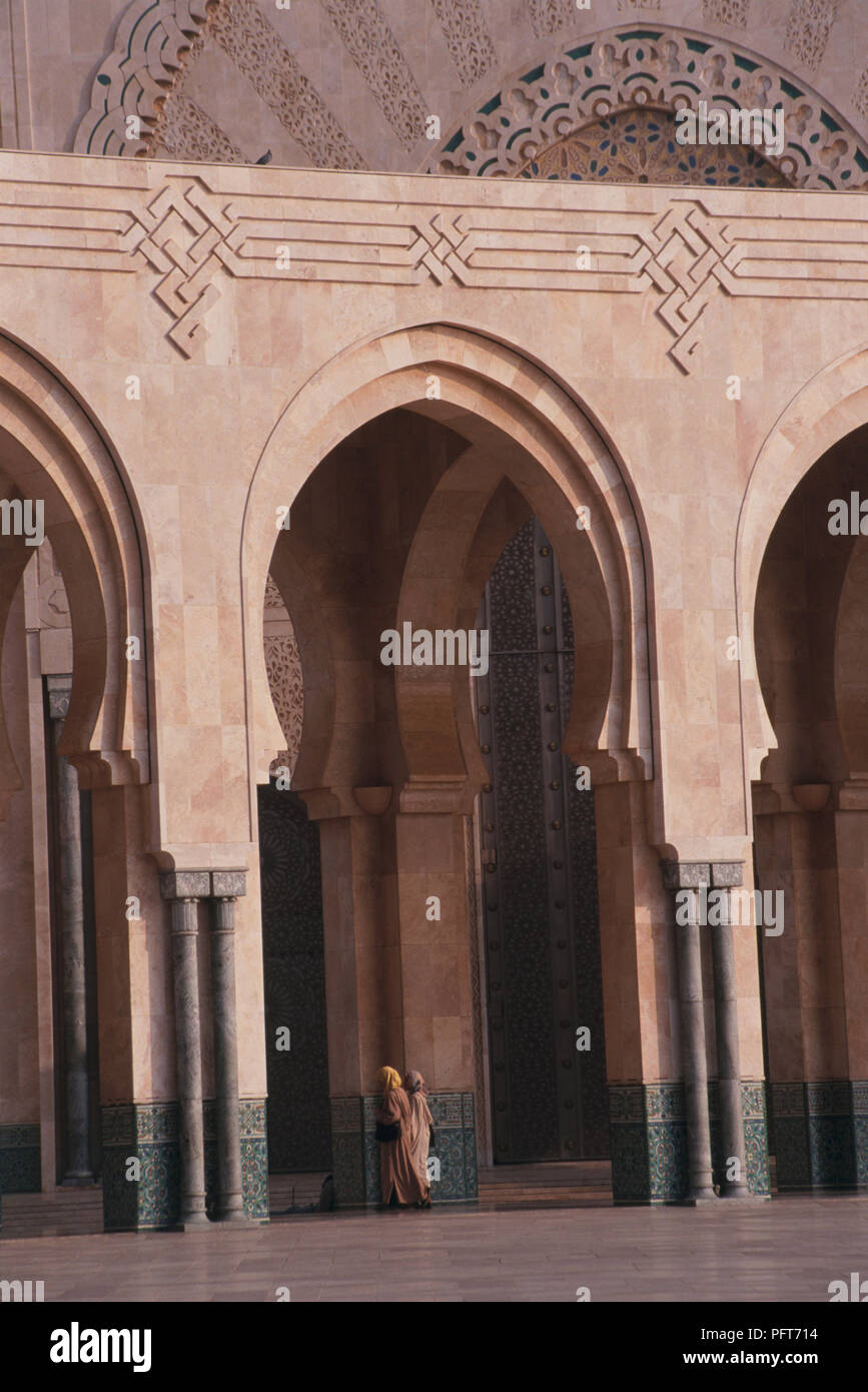 Morocco, Casablanca, Grand Mosque, Muslim women wearing traditional clothing entering mosque through horseshoe arch Stock Photo
