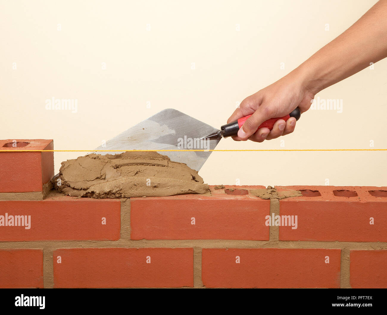 Building a brick wall, placing mortar on to bricks with a trowel Stock