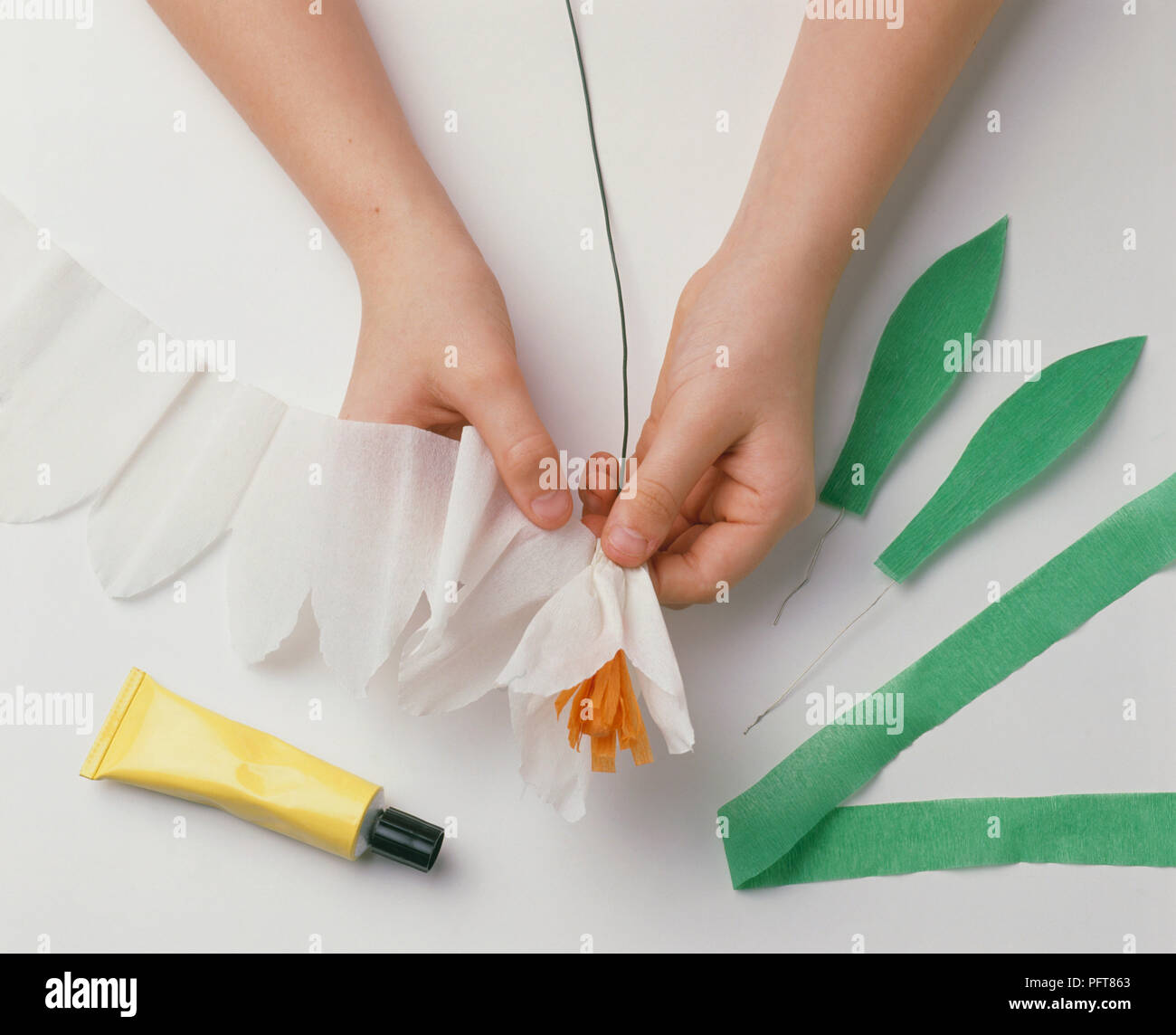 Child's hands wrapping white crepe paper around wire to make paper flower Stock Photo Alamy