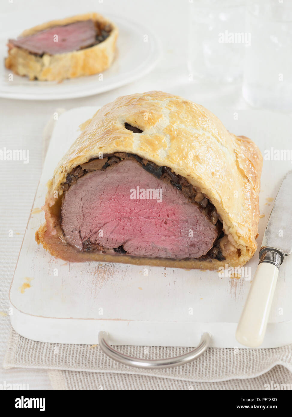 Beef en croute (Beef Wellington) on chopping board and slice on plate