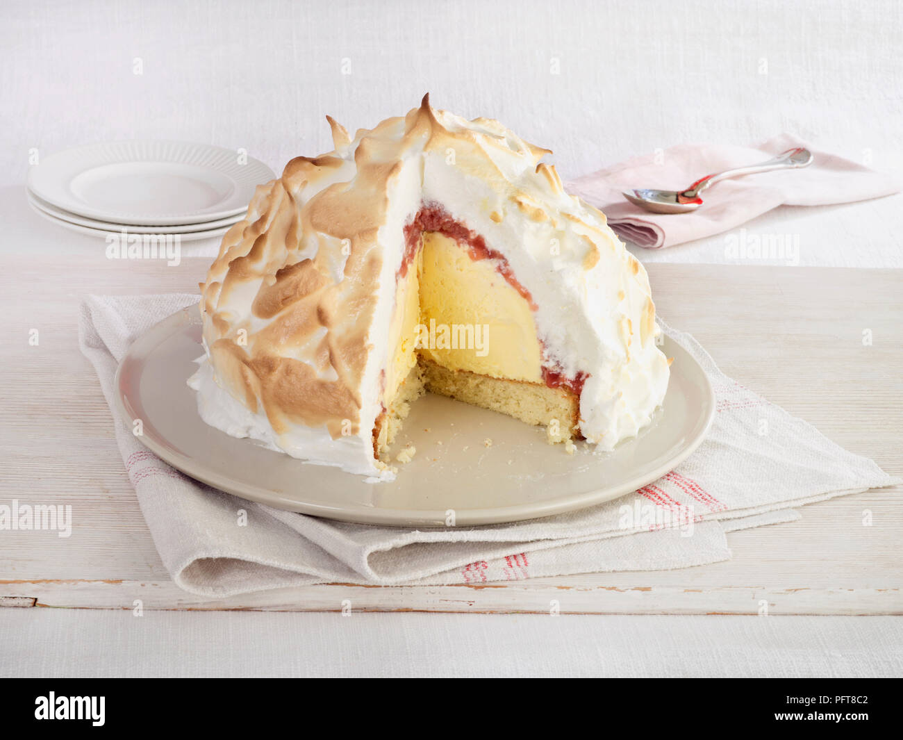 Baked Alaska with slice removed showing ice cream and sponge cake with
