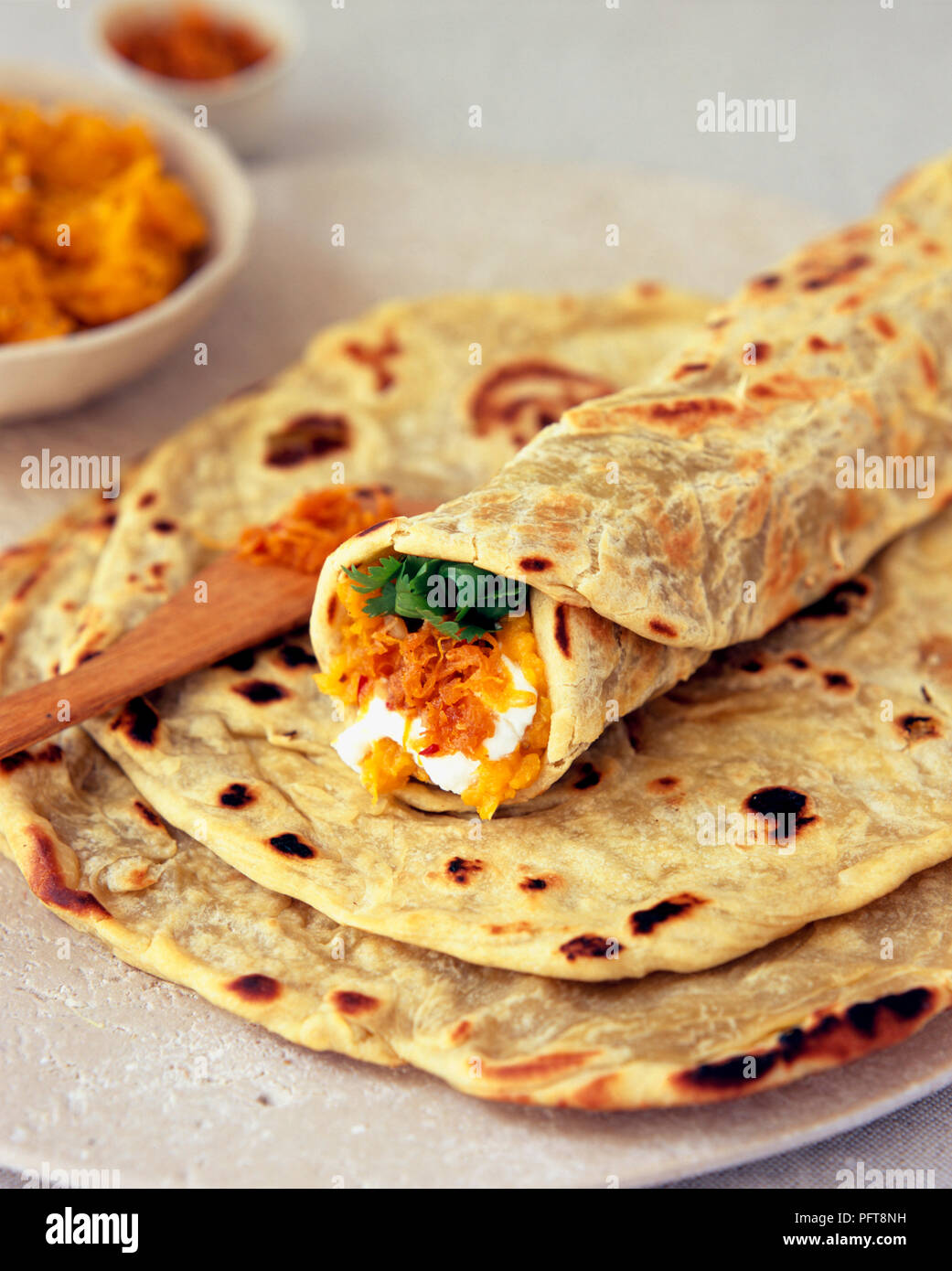 Bolani (Afghani flat breads) in a pile, the top one rolled up and filled with roast pumpkin paste, carrot pickle and fresh parsley Stock Photo
