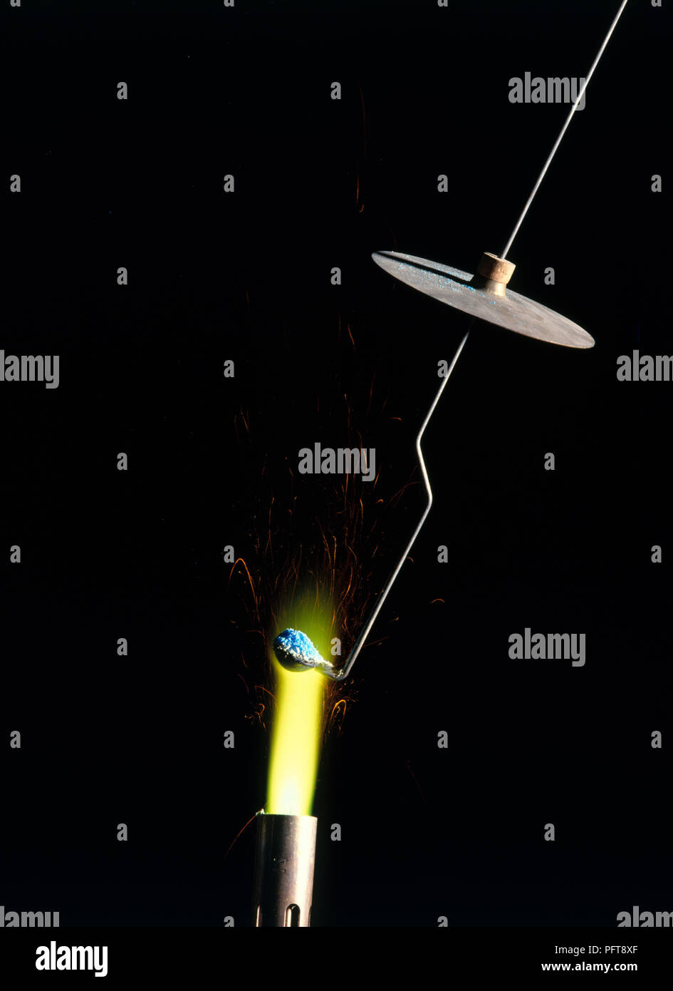 Flame experiment holding copper compound on platinum wire in Bunsen Burner flame, turning flame yellow Stock Photo