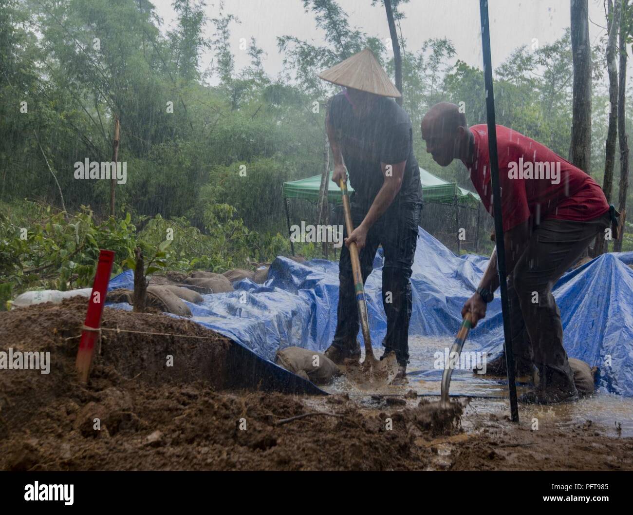 U.S. Army Staff Sgt. Joel Brigham, Defense POW/MIA Accounting Agency (DPAA) medic, left, and U.S. Marine Corps Sgt. Brandon Swain, DPAA recovery noncommissioned officer augmentee, dig trenches for overflowing rain water during a DPAA recovery mission in Khammouan province, Lao People’s Democratic Republic, May 23, 2018. DPAA team members deployed to the area in hopes of locating U.S. service members who went missing from the Vietnam War. The mission of DPAA is to provide the fullest possible accounting for our missing personnel to their families and the nation. Stock Photo