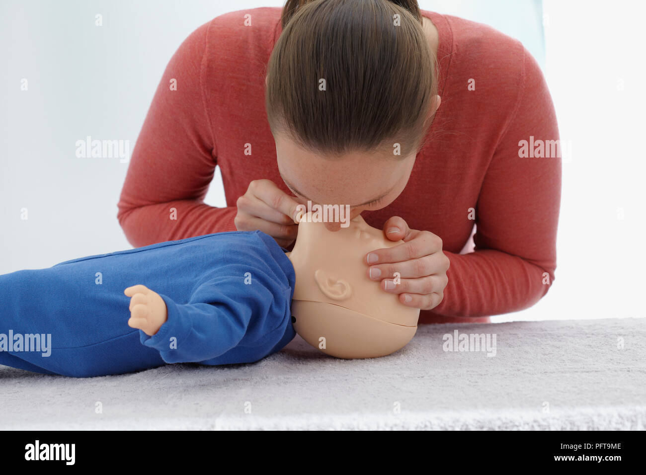 First aid medical checks and treatment of unconscious infant, using dummy, mouth to mouth, giving CPR Stock Photo