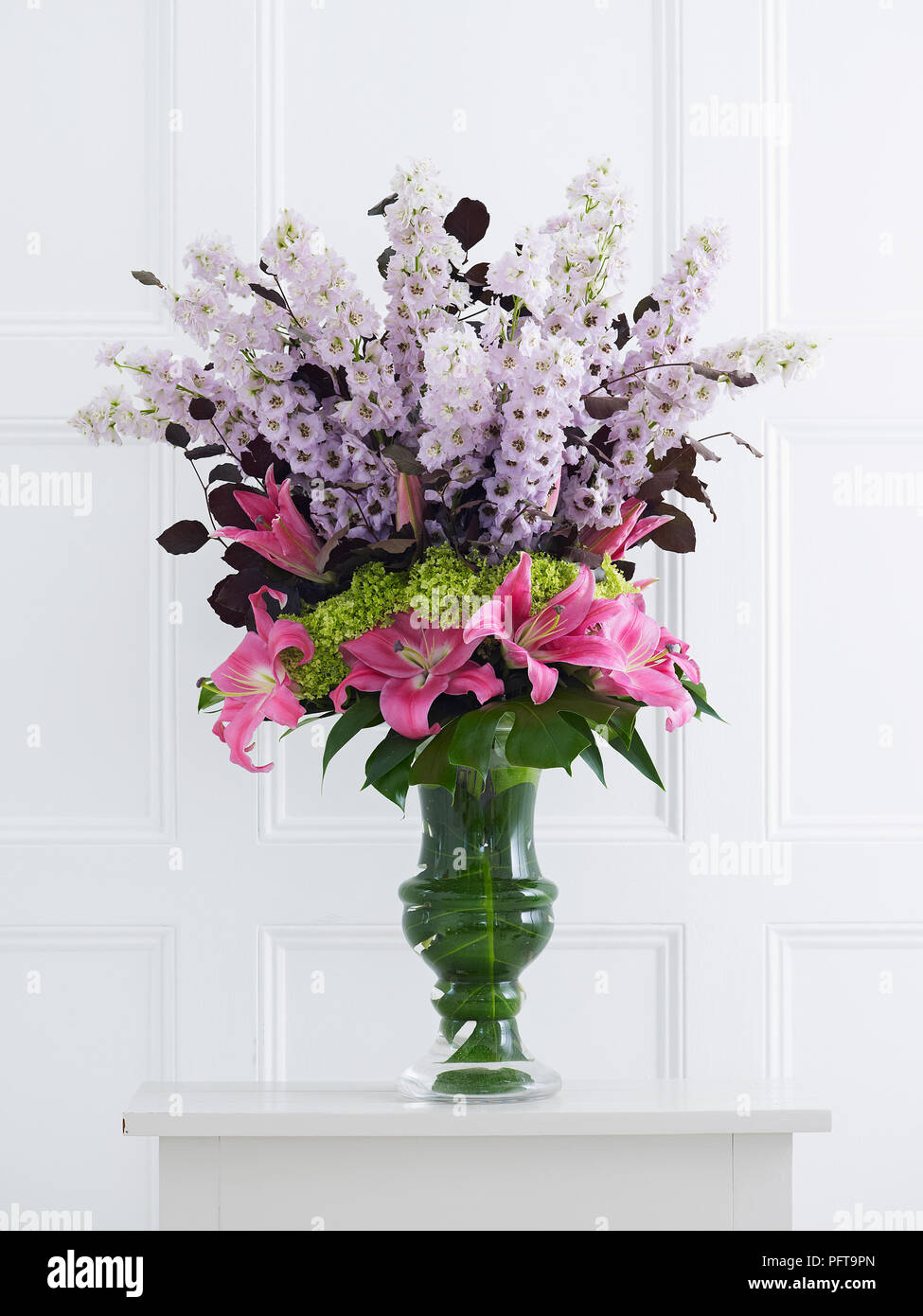 Layered flower arrangement in vase, delphinium, hydrangea, lily, copper beech leaves Stock Photo