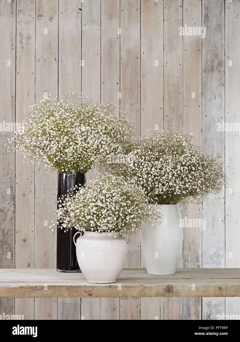 Gypsophila Flowers In Vases Of Different Shapes Against Wooden
