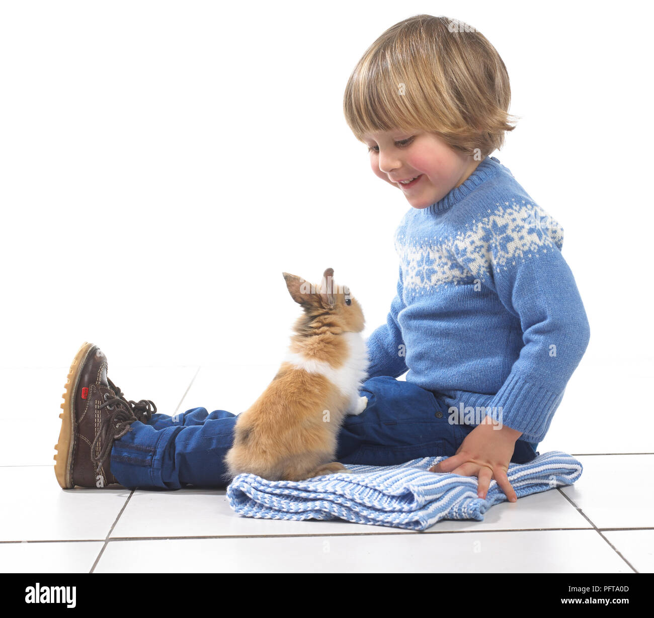Boy sitting with rabbit on blanket, 3 years Stock Photo