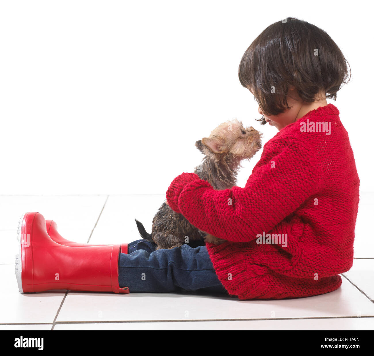 Young girl sitting looking down at her puppy, 2 years Stock Photo
