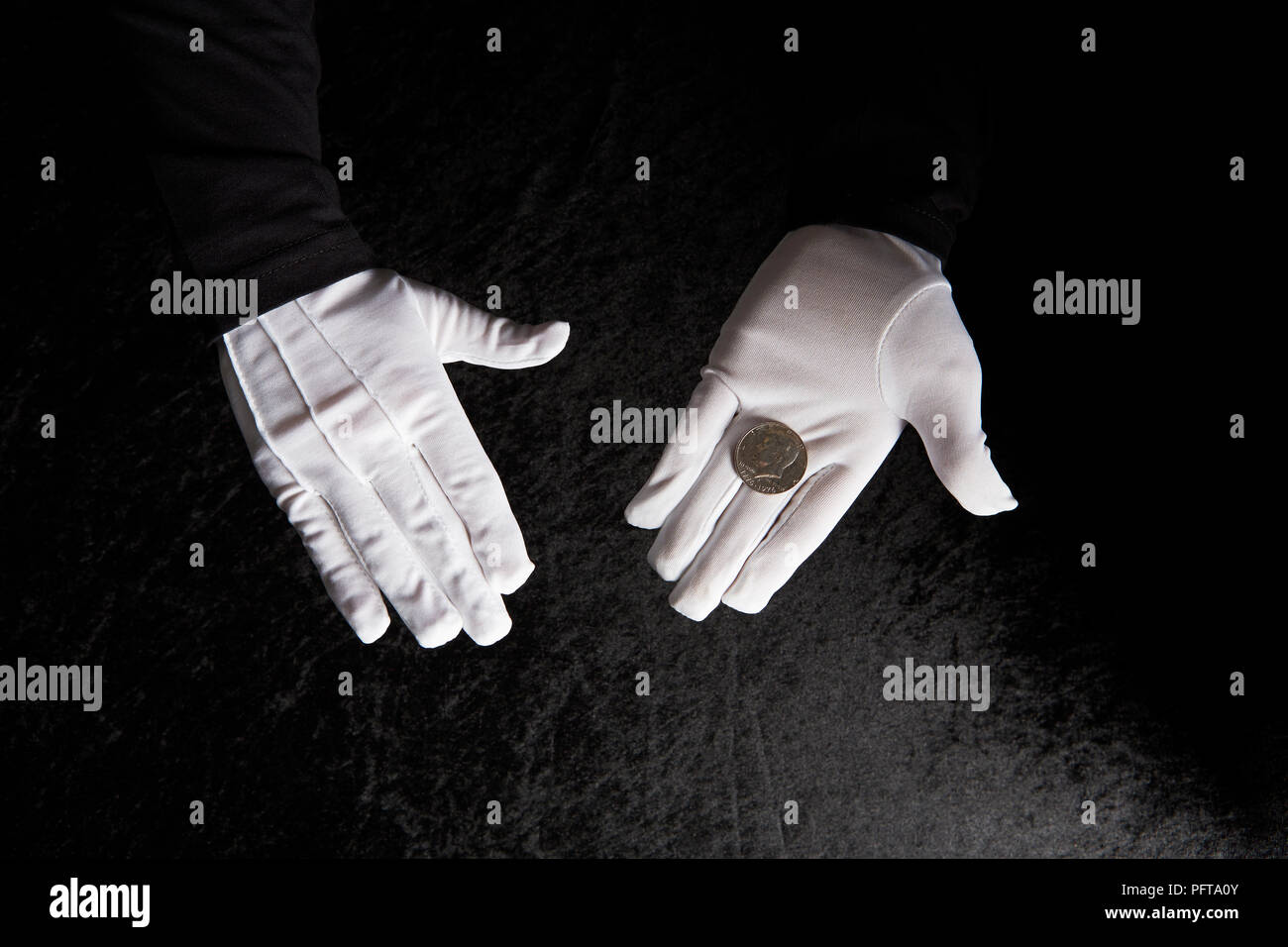 Gloved hands holding coin Stock Photo