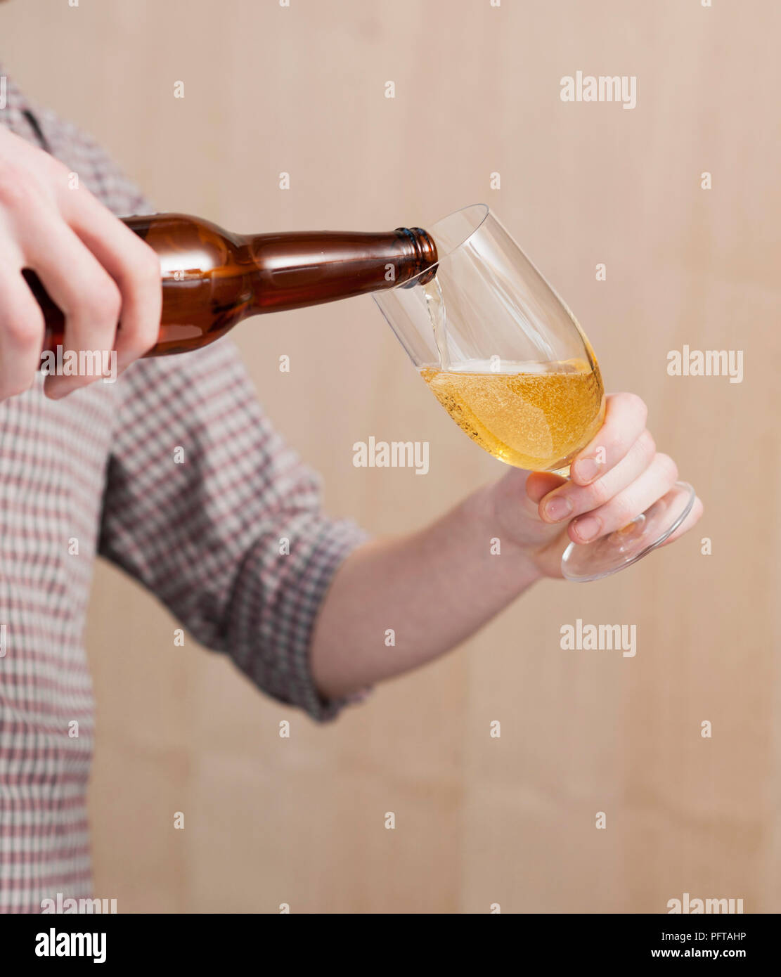 Pouring beer into glass, holding glass at angle Stock Photo