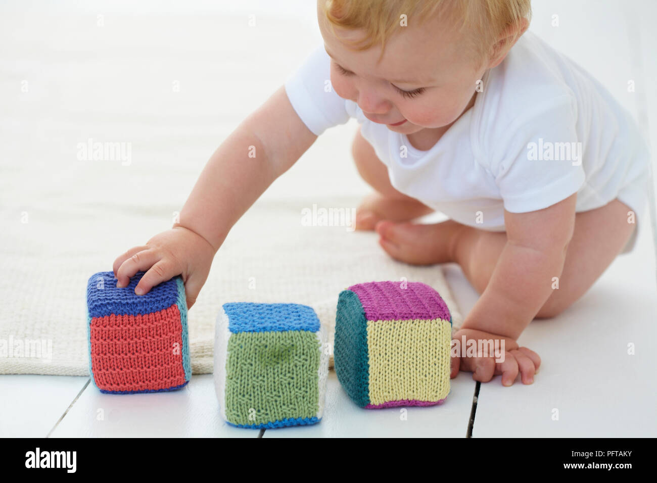 Baby boy playing with knitted stacking blocks, 10 months Stock Photo - Alamy