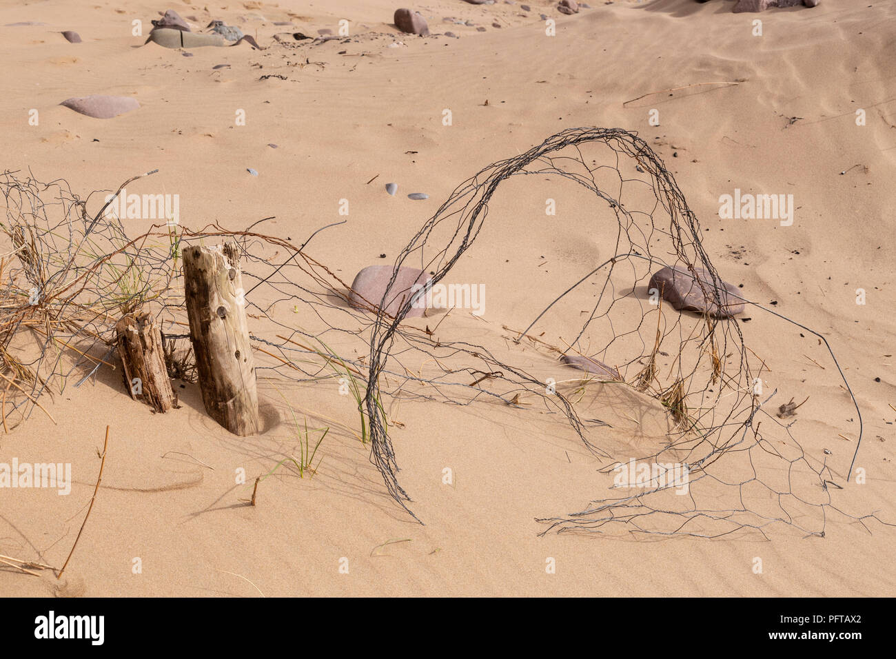 Broken wire fence on the beach at Rhossili on the South Wales coast Stock Photo