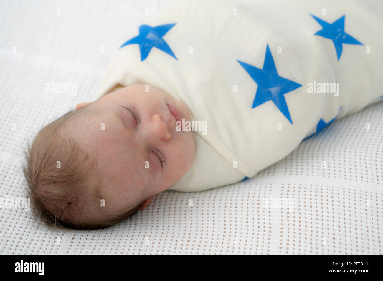 Baby boy swaddled in star print blanket, 7 weeks Stock Photo