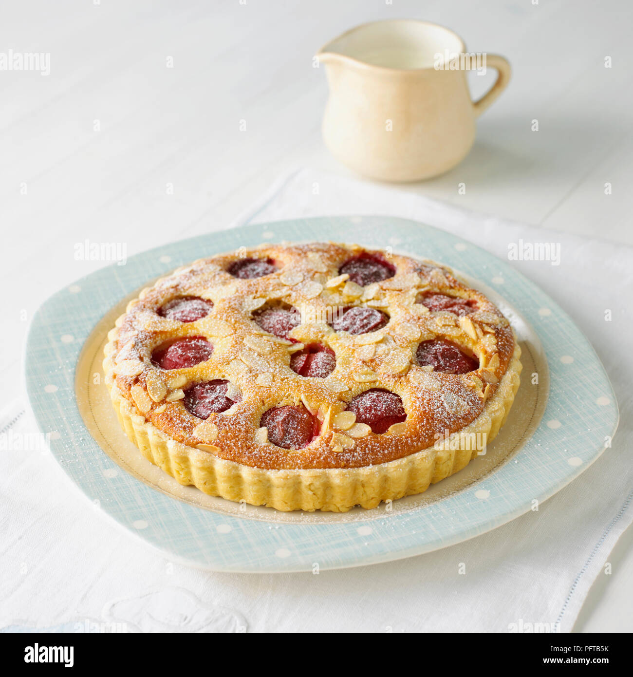 Plum tart topped with almond flakes and icing sugar Stock Photo