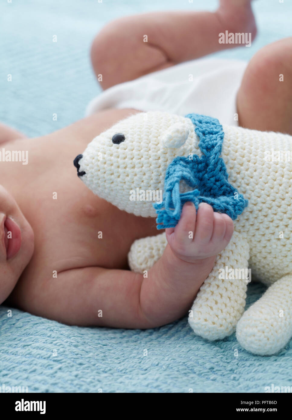 Baby girl cuddling crocheted polar bear, 4.5 months Stock Photo