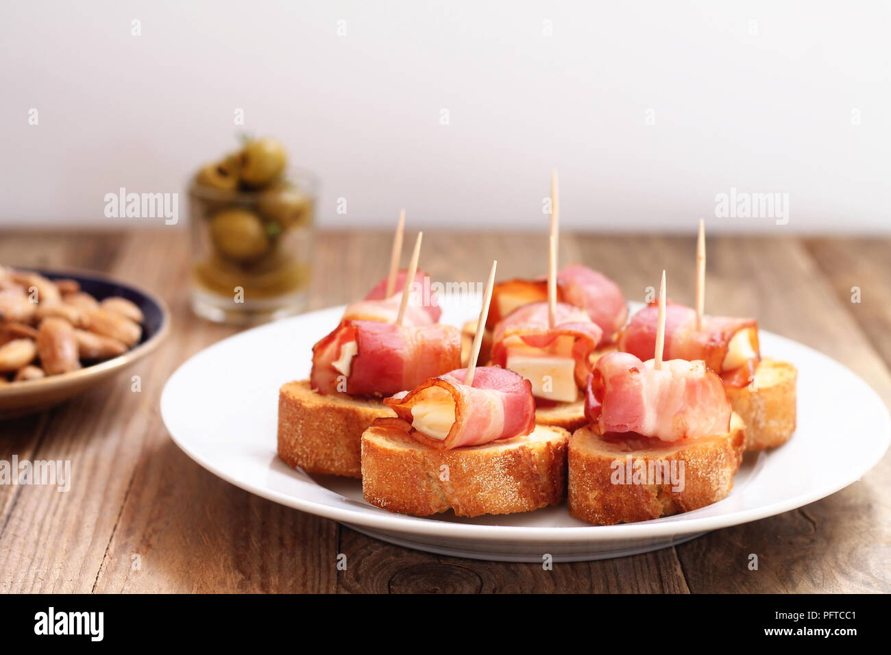 Spanish tapas - bites made of bread, melted cheese and bacon, with fried  almonds and olives Stock Photo - Alamy