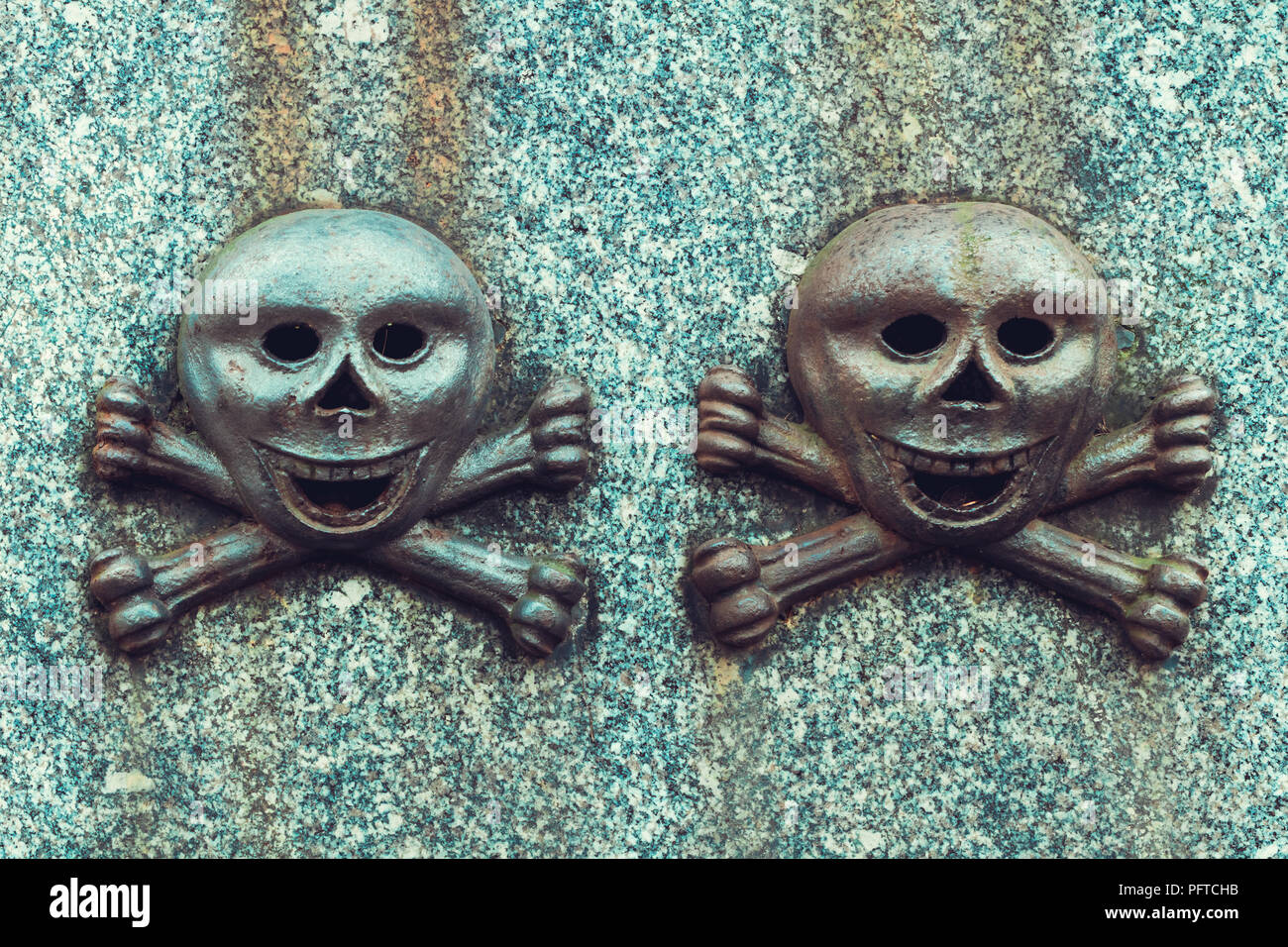 Details on an old gravestone. To smiley skulls with bones. Stock Photo