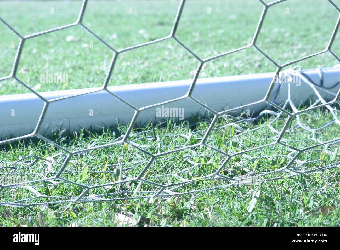 Detail of soccer goal with net resting on green grass of soccer pitch - landscape orientation Stock Photo