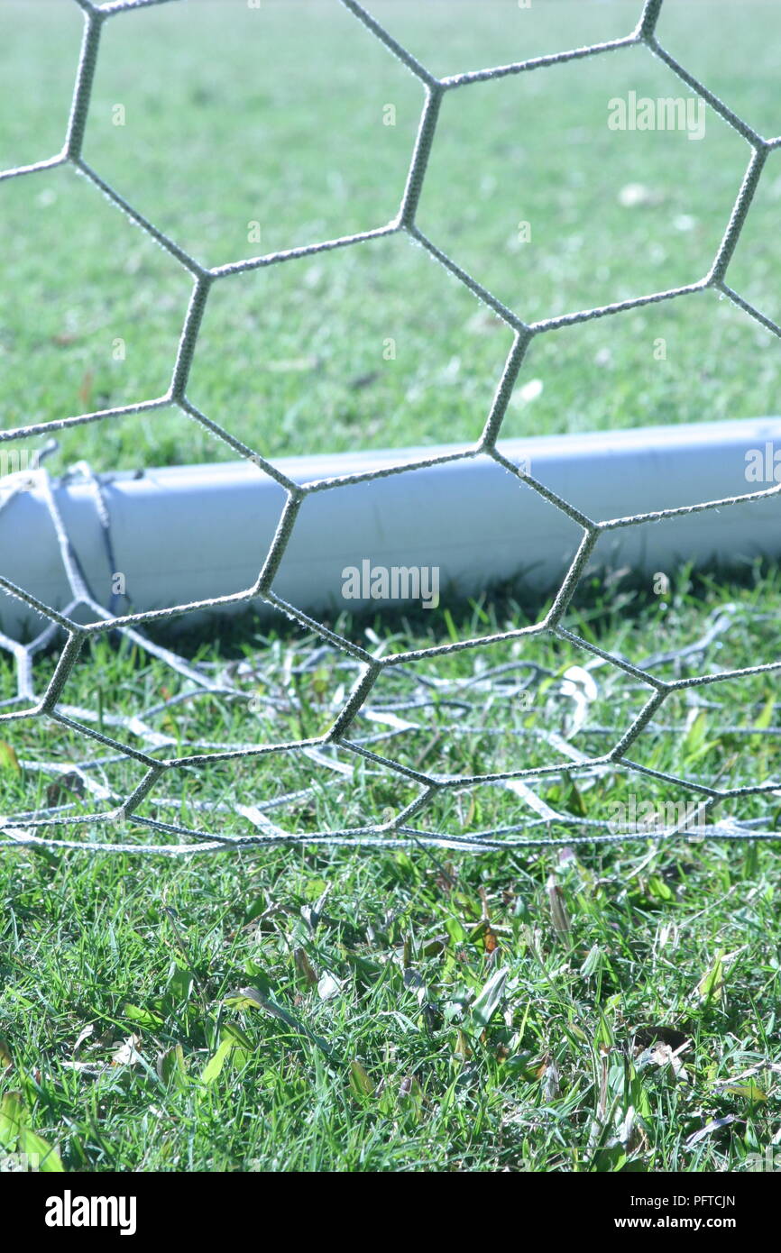 Detail of soccer goal with net resting on green grass of soccer pitch - portrait orientation Stock Photo