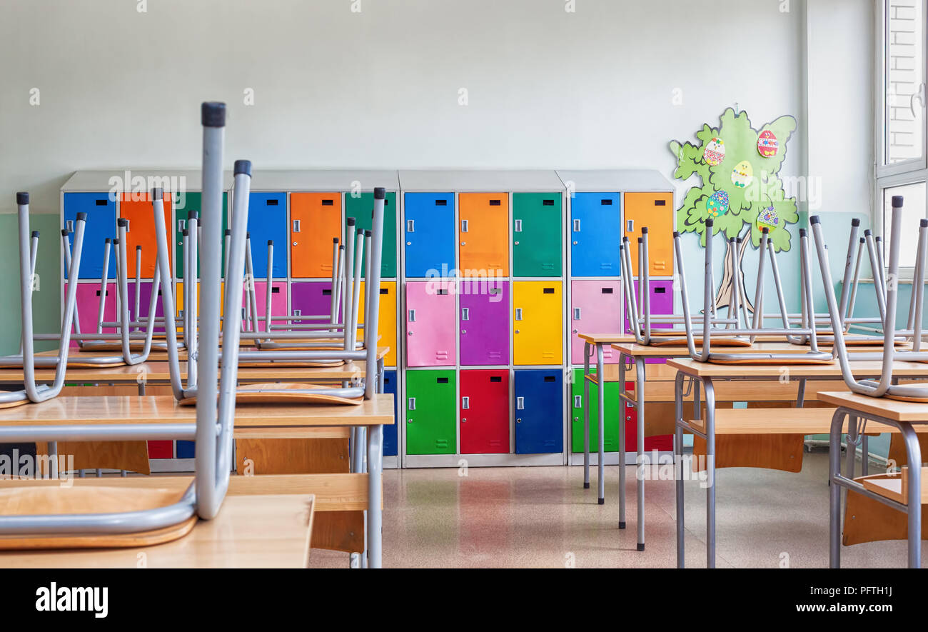 Modern emty classroom with colorful lockers and raised chairs on the tables Stock Photo