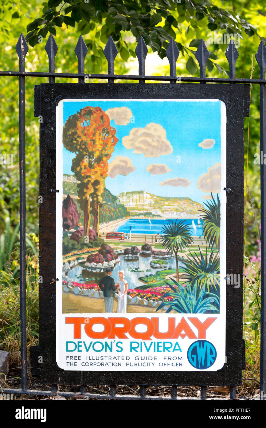 Vintage travel poster (GWR railway) fixed outdoors to railings at train station on a heritage railway line in UK, advertising Torquay, Devon's Riviera. Stock Photo