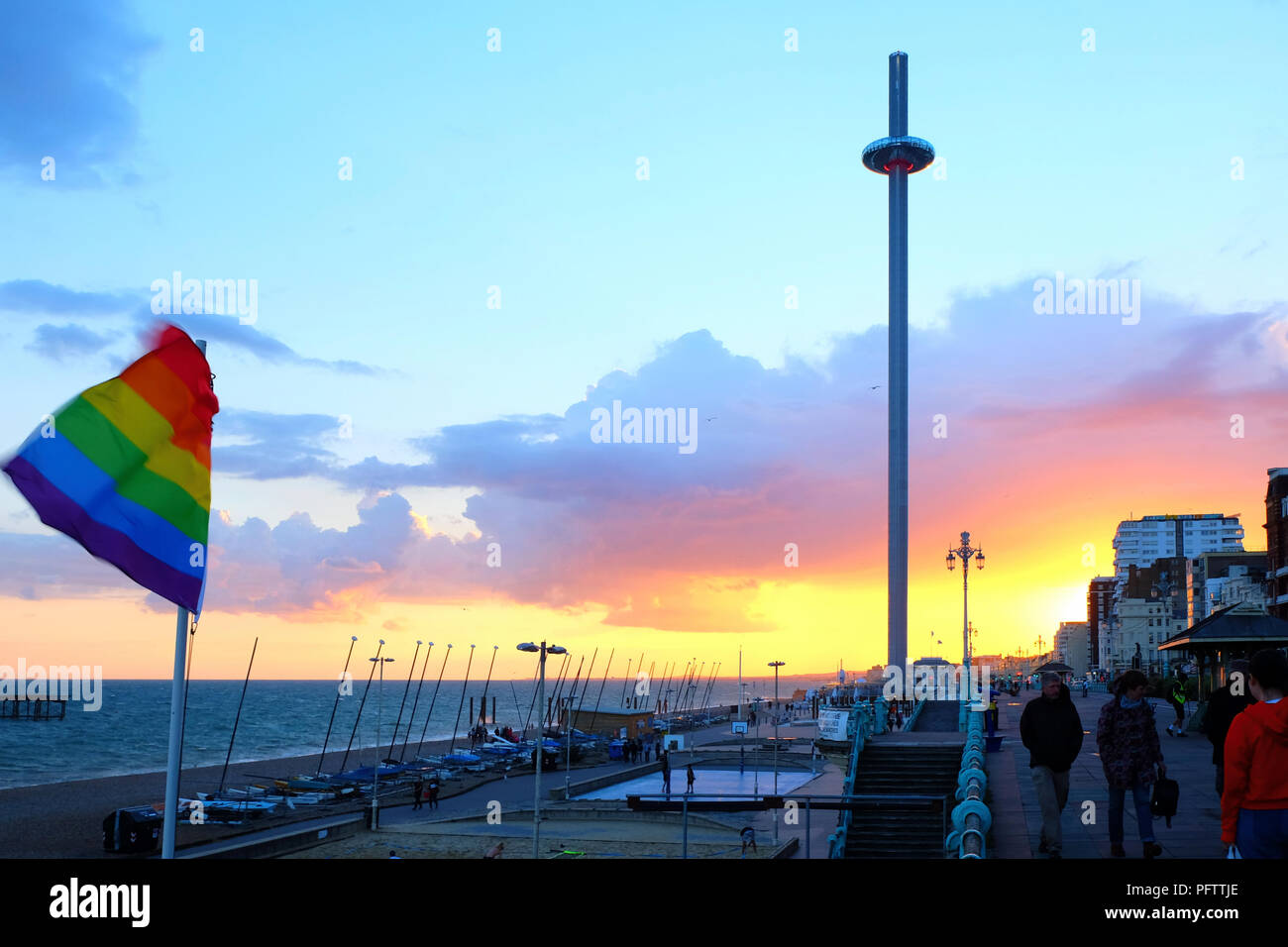 Brighton promenade at sunset with the moving viewing tower in the centre the promenade is very busy a pride flag is flying in the background the sky i Stock Photo