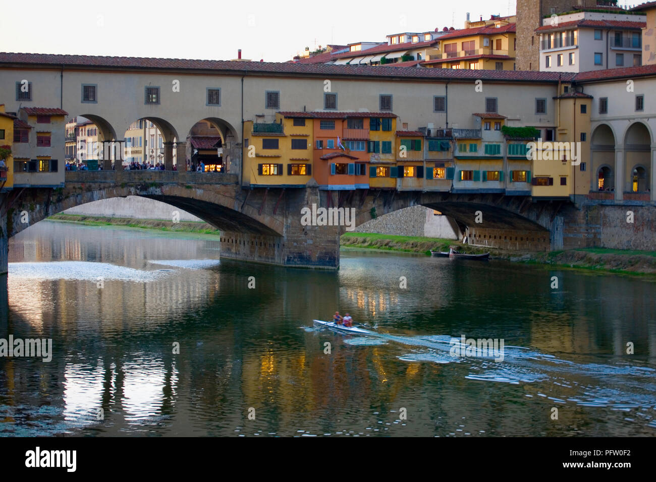 Dusk over the river Arno in Florence, Tuscany, Italy, with the Ponte Vecchio spanning the river and a double scull in foreground Stock Photo