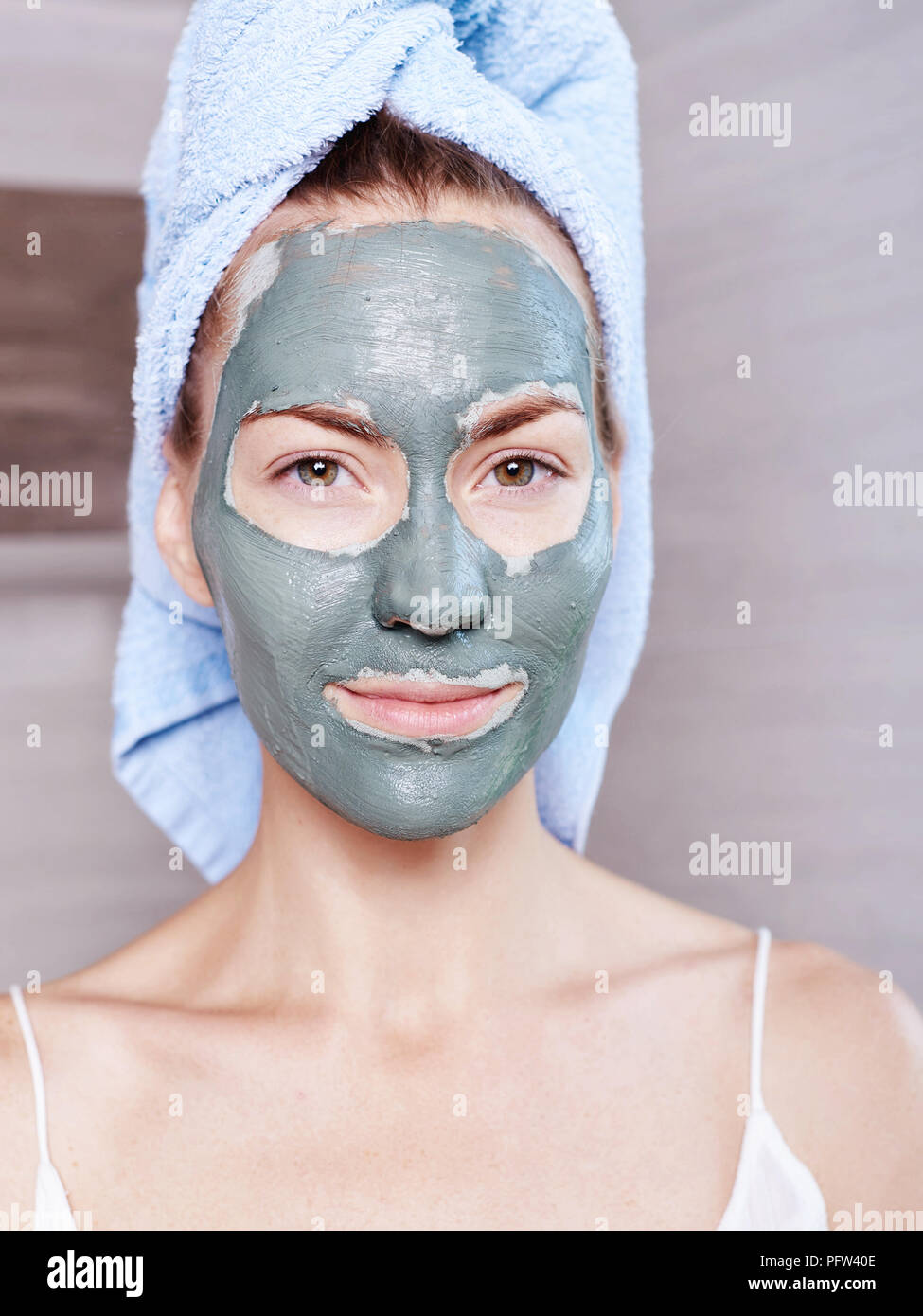 Woman applying mask moisturizing skin cream on face looking in bathroom