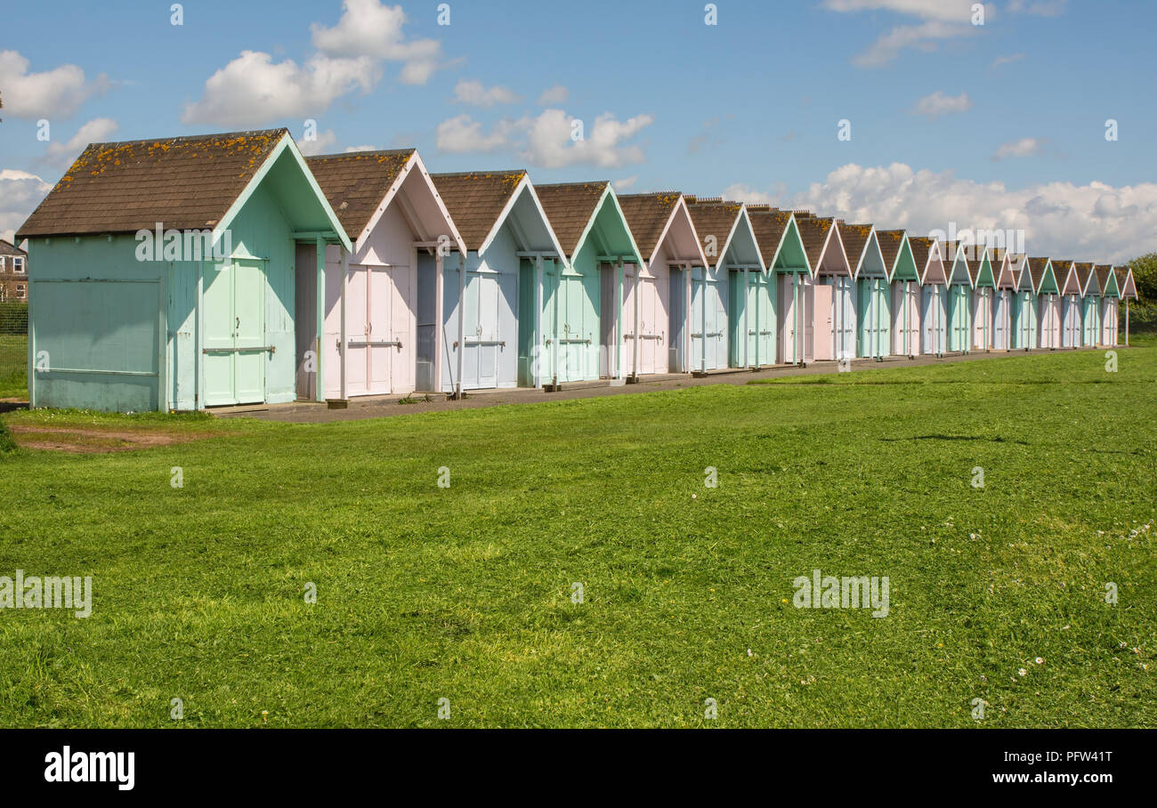 Row of multicoloured beach huts on green behind seafront at Southsea in Portsmouth, Hampshire, England Stock Photo