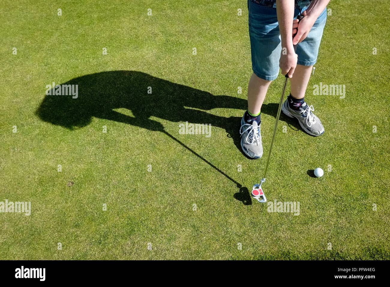 Legs of a young boy teenager preparing to put a golf ball. Cornwall Polzeath Stock Photo