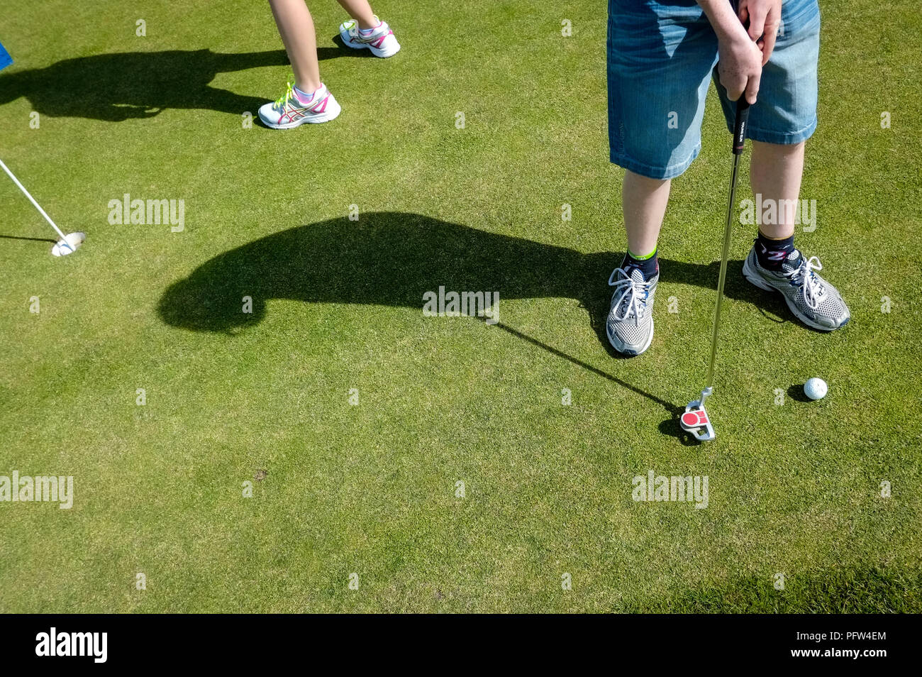 Legs of a young boy teenager preparing to put a golf ball. Cornwall