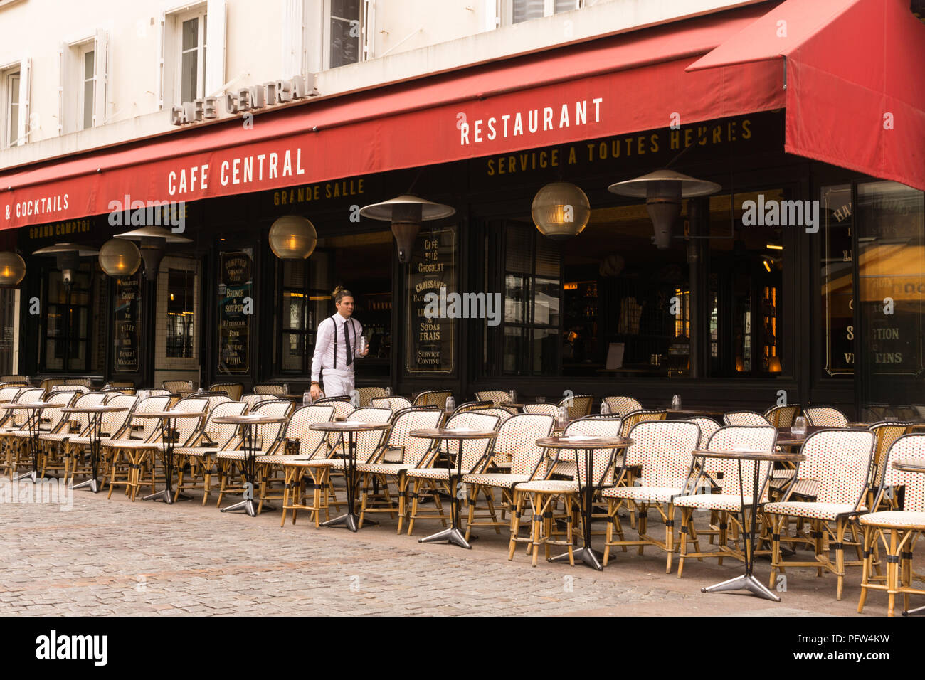 Paris waiter - A Parisian waiter sets the tables at the Cafe Central restaurant on Rue Cler in Paris, France, Europe. Stock Photo