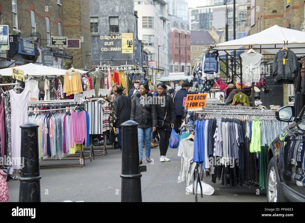 View of people walking between outdoor racks of clothing that line a pedestrian street at Petticoat Lane Market, located in the East End, in London, England, October 29, 2017. () Stock Photo