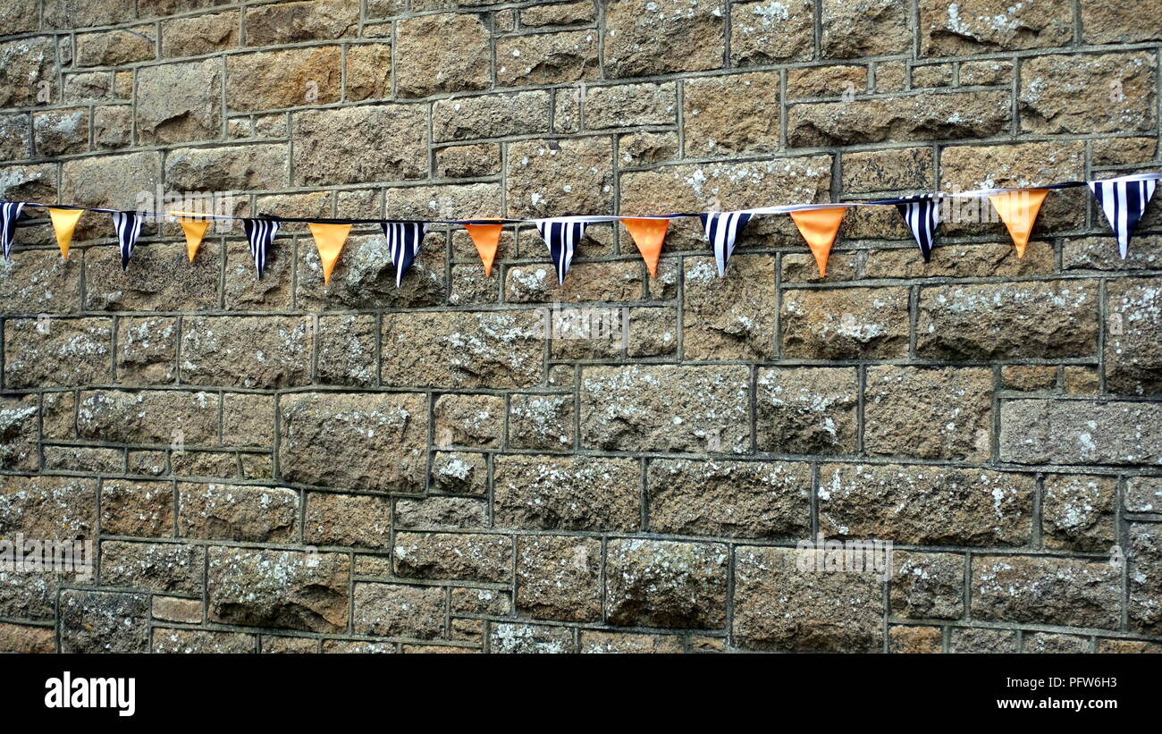 Bunting or pennants in navy blue, white and orange, hanging on a grey