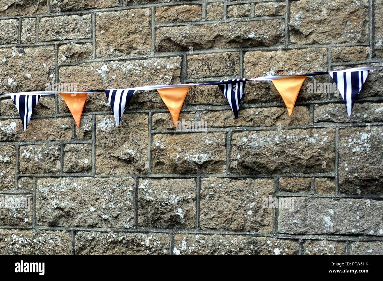 Bunting or pennants in navy blue, white and orange, hanging on a grey